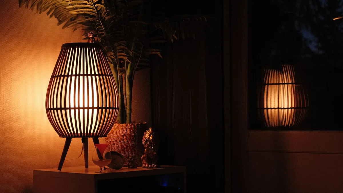 A warm wooden lamp casts a cozy glow in an indoor setting, reflecting softly on nearby surfaces.