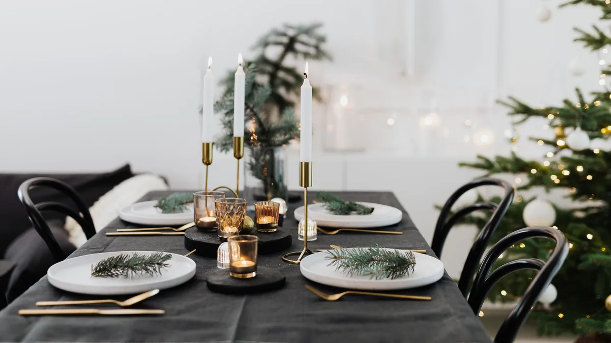 Festive Christmas table setting adorned with candles, pine branches, and elegant tableware.