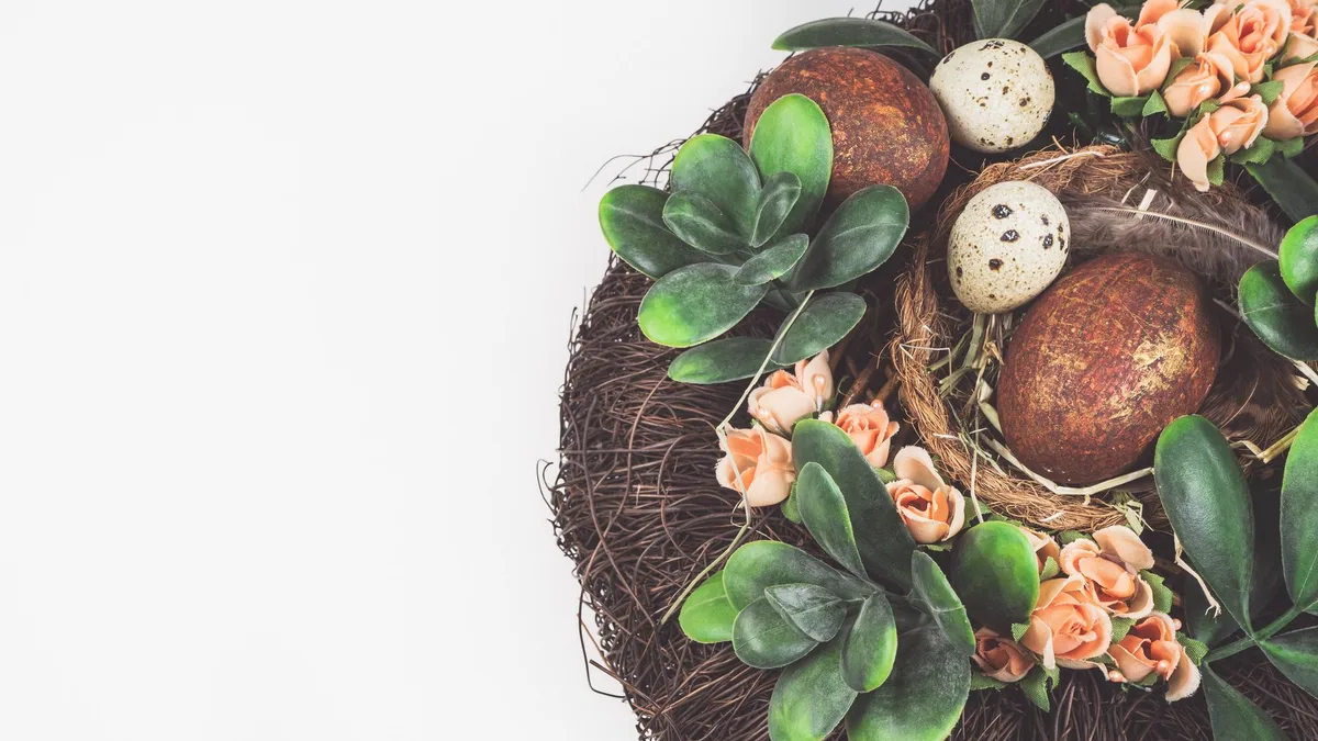 A beautiful springtime arrangement of an Easter nest with decorative eggs, flowers, and greenery.