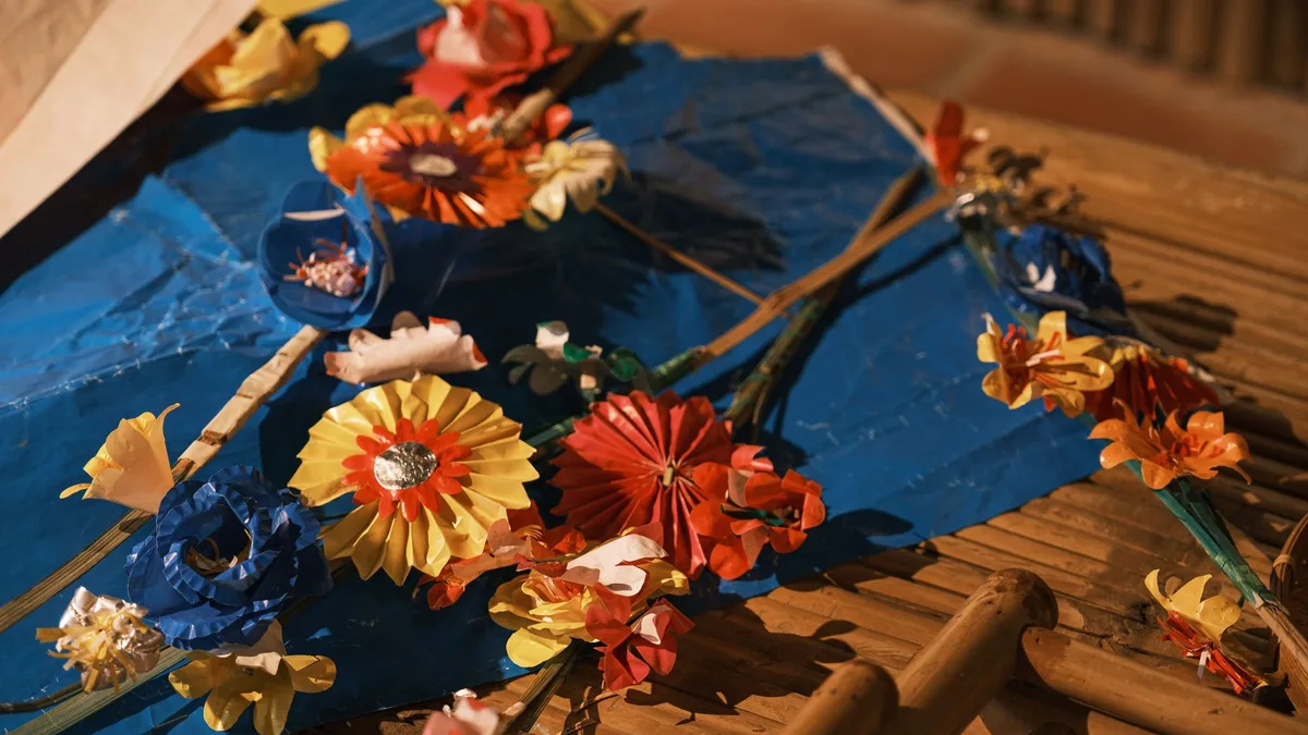 Vibrant handmade paper flowers arranged on a natural bamboo surface for a creative craft display.
