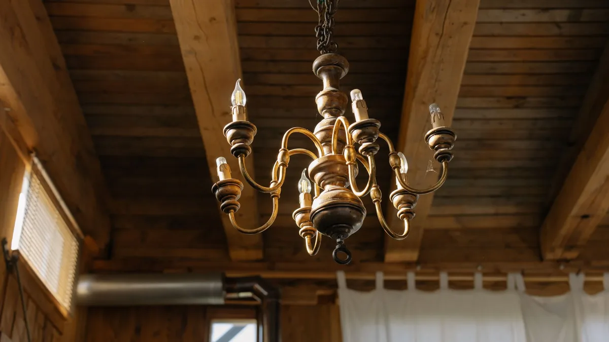 Elegant chandelier hanging from a rustic wooden ceiling, capturing a classic and antique interior decor.