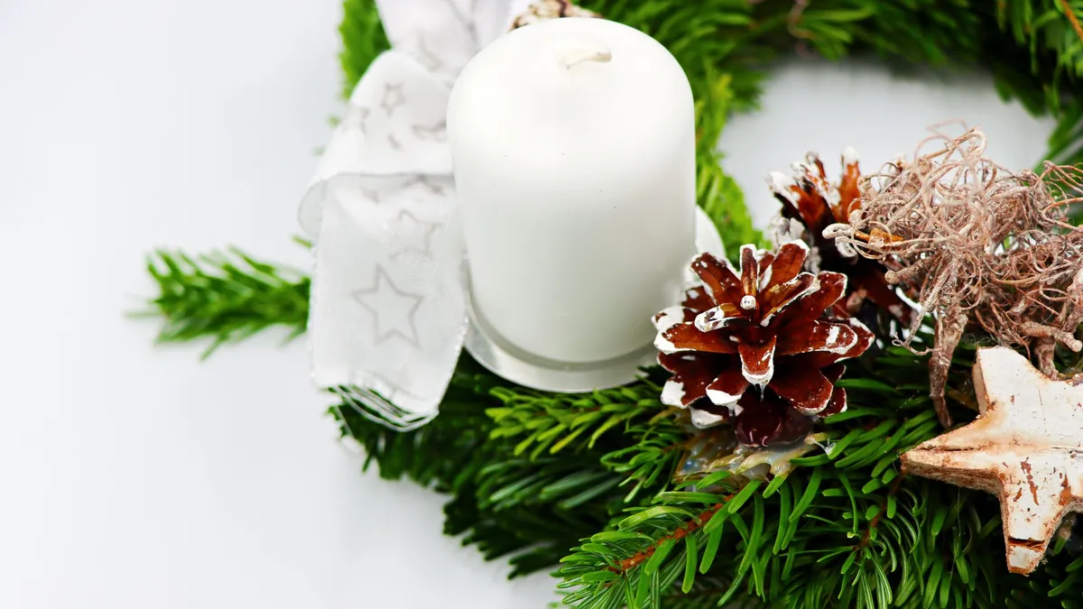 Rustic Christmas wreath made from evergreen, pinecones, and a white candle for festive decor.