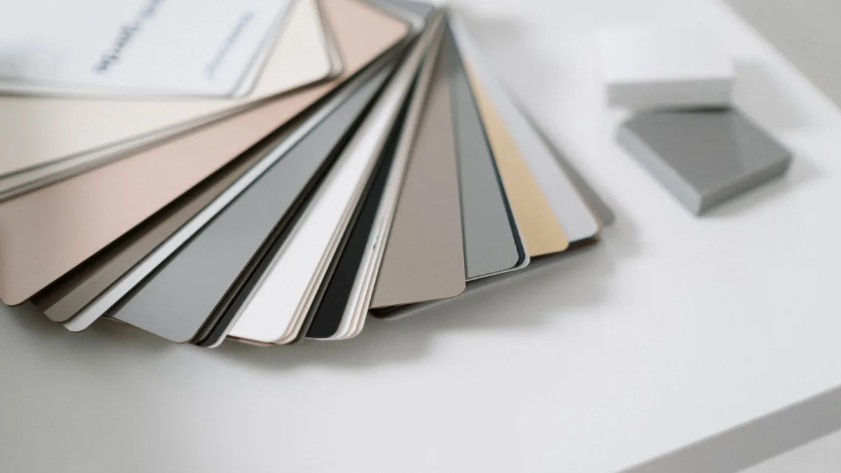 A variety of neutral color samples on a minimalist white desk for design purposes.