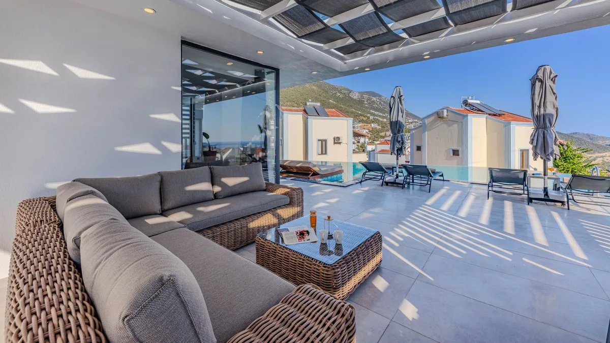 Luxurious outdoor terrace with seating, overlooking mountains and a pool.